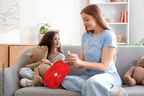 Little girl with toy and her mother taking inhaler from first aid kit at home photo