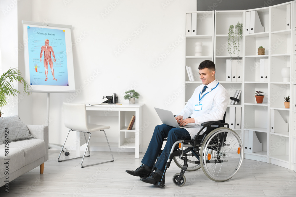 Young male doctor in wheelchair with laptop at hospital Young male doctor in wheelchair with laptop at hospital