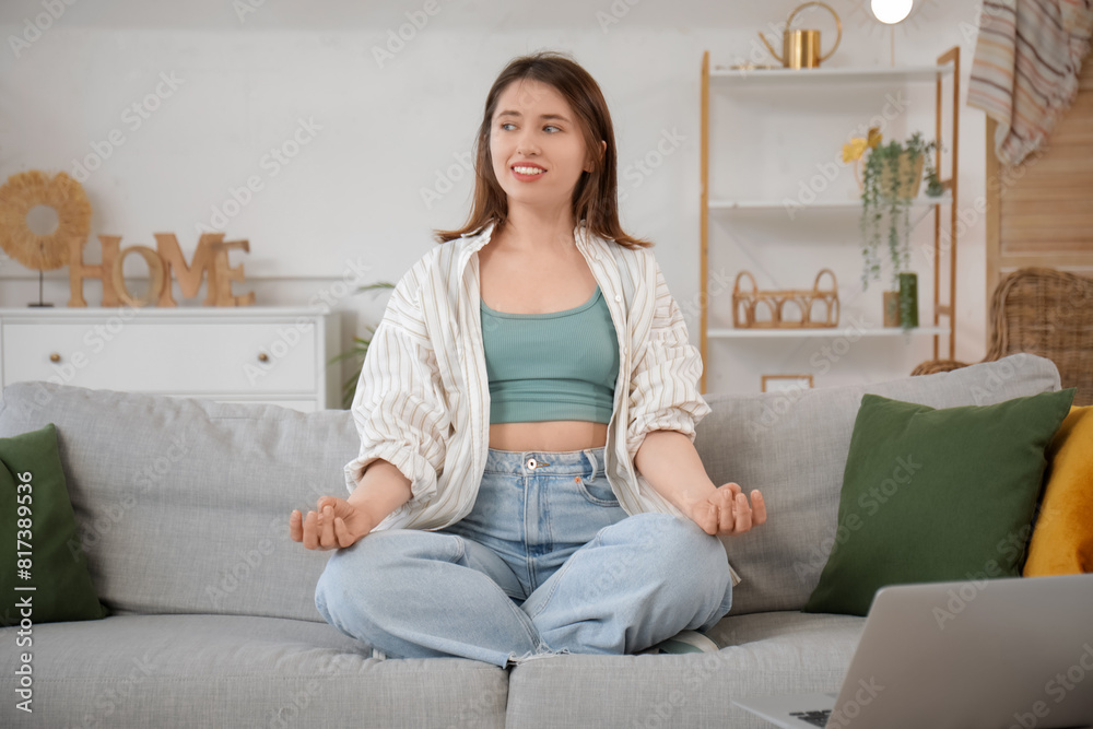 Happy young woman meditating on cozy sofa at home Happy young woman meditating on cozy sofa at home