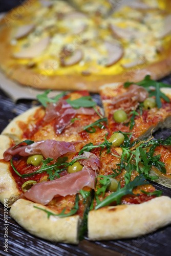 Pizzas with jamon, arugula, pear and cheese on a wooden surface.