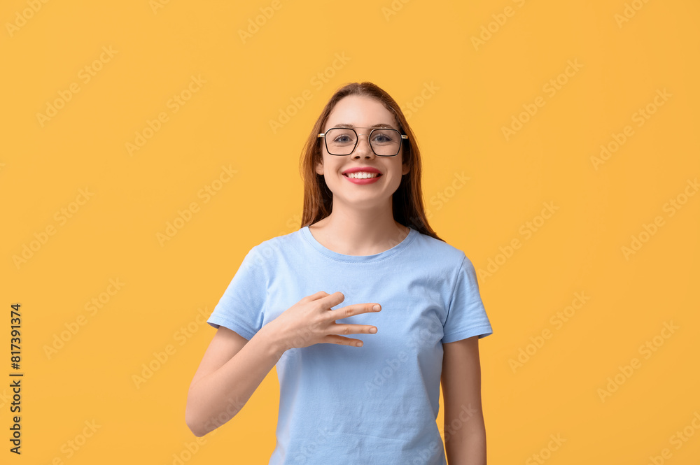 Young deaf mute woman using sign language on orange background Young deaf mute woman using sign language on orange background