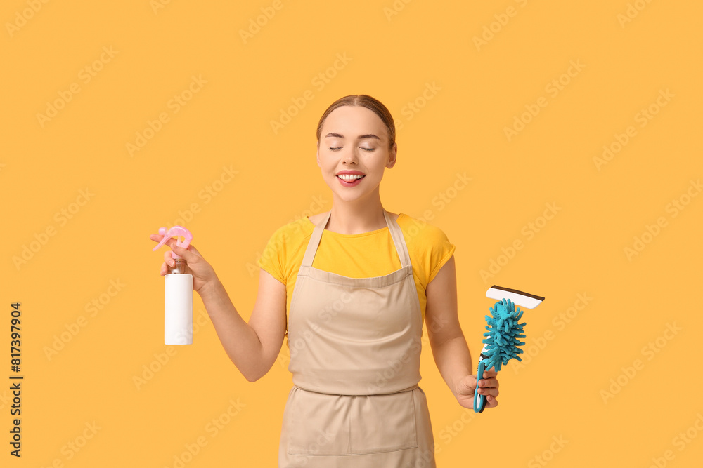 Pretty young woman with cleaning supplies on orange background Pretty young woman with cleaning supplies on orange background