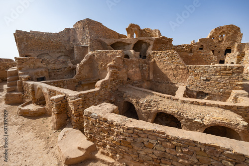 Eroded stone walls and arches of fortifications of Ksar Beni Barka standing under blue Tunisian sky, showcasing traditional Berber architecture in Tataouine photo