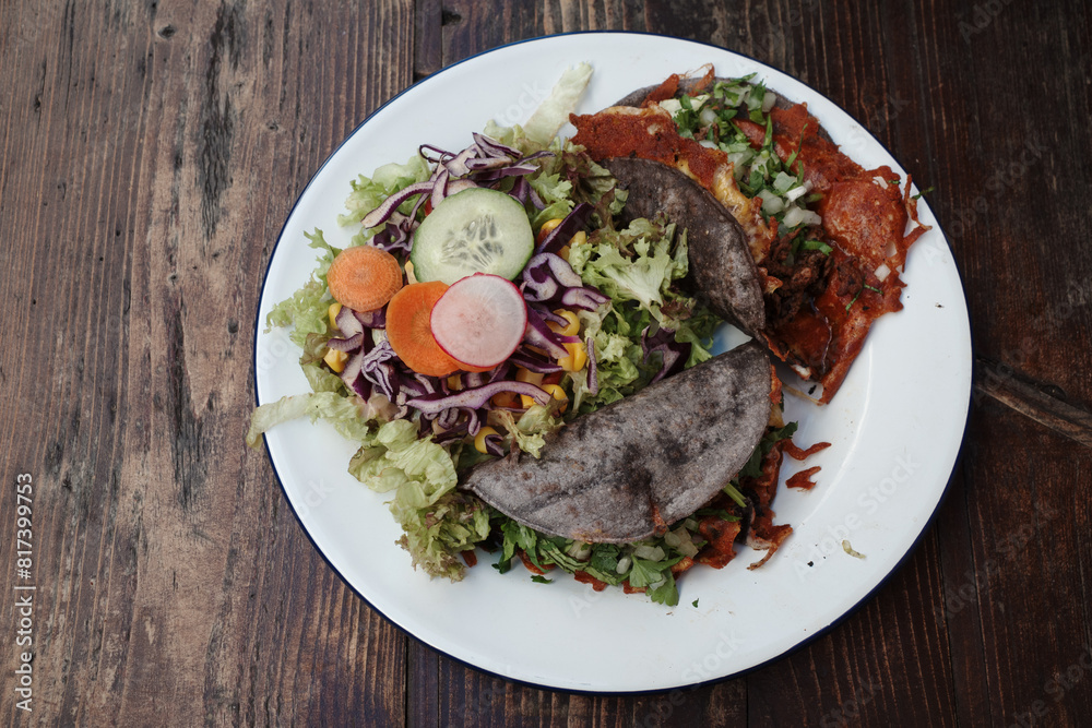 A delicious plate featuring two tacos and a side of fresh salad. The tacos are filled with savory ingredients and wrapped in blue corn tortillas. A delicious plate featuring two tacos and a side of fresh salad. The tacos are filled with savory ingredients and wrapped in blue corn tortillas.