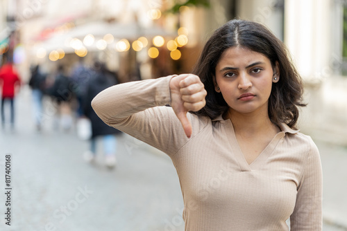 Dislike. Upset Indian young woman showing thumbs down sign gesture, expressing discontent, disapproval, dissatisfied bad work, mistake outdoors. Displeased girl on urban city street. Town lifestyles