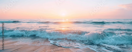 Calm ocean waves at sunset with a clear sky above. The serene water reflects the soft pastel hues of the setting sun  creating a peaceful and tranquil seascape.