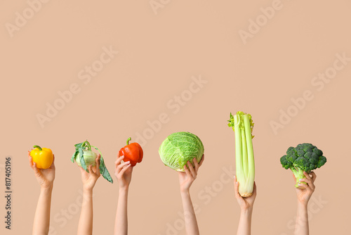 Female hands holding fresh vegetables on beige background photo