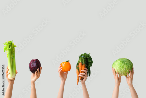 Female hands holding fresh vegetables on grey background photo