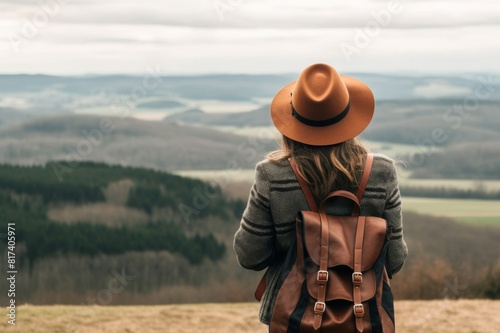 Woman wearing hat standing with backpack on mountain