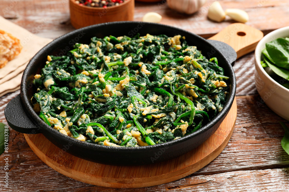 Tasty spinach dip with eggs in dish served on wooden table, closeup Tasty spinach dip with eggs in dish served on wooden table, closeup