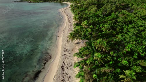 Aerial rotating view of remote, uninhabited tropical island with turquoise water and dense forest in Spain. photo