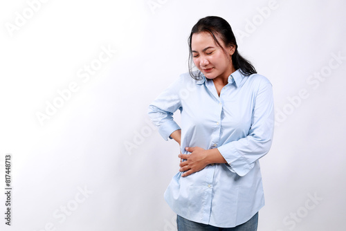 Asian woman is suffering from stomach pain in the right side with hands feeling acute pain. Stomach-ache concept. Isolated on white background