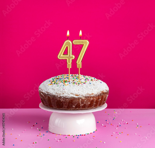 Lighted birthday candle number 47 - Birthday card on pink background