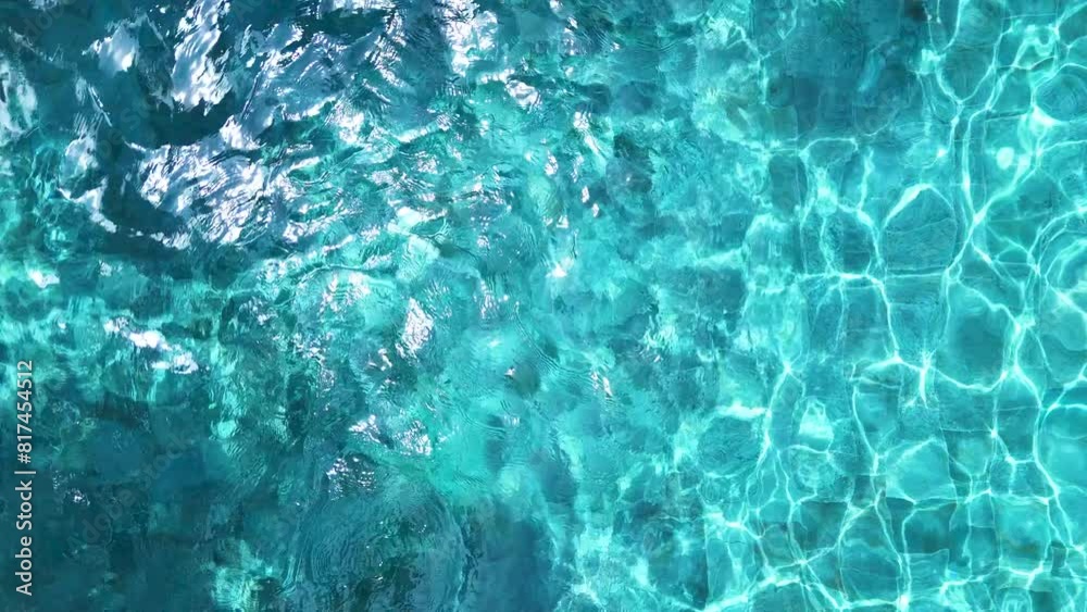 Shooting from a drone, blue water in an outdoor pool with reflections of light.