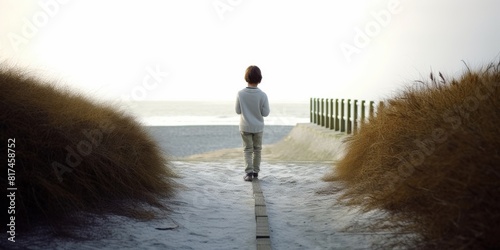boy standing in path on beach, folding arms
