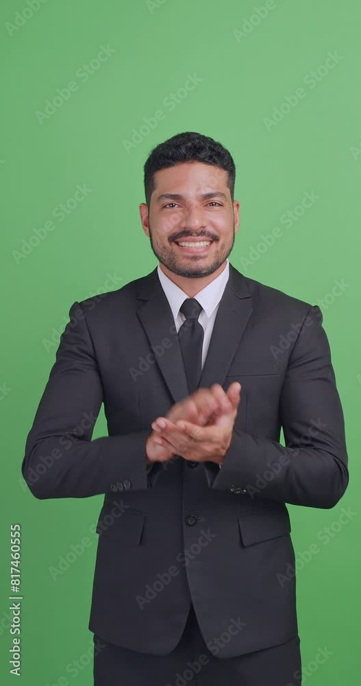 Vertical clip. Asian businessman in a black suit is clapping his hands to congratulate on something. Isolated on green background in studio. Vertical clip. Asian businessman in a black suit is clapping his hands to congratulate on something. Isolated on green background in studio.