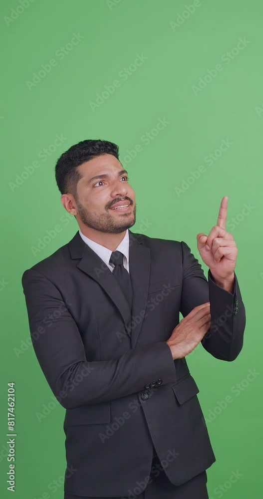 Vertical clip. Asian businessman in a black suit showing something or copy space for product or sign text. Isolated on green background in studio. Vertical clip. Asian businessman in a black suit showing something or copy space for product or sign text. Isolated on green background in studio.