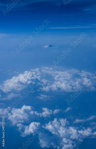 view of the bright blue sky and mountains on the island of Java from the plane window, blue sky with clouds, See Through Plane Window With Blue Sky And Clouds Outside, travel trip over Java island © Fani