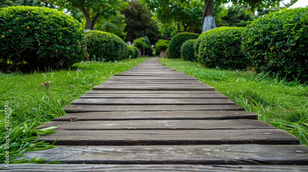 Straight wooden walkway in the park with green lawn, trees and bushes, landscape design Straight wooden walkway in the park with green lawn, trees and bushes, landscape design