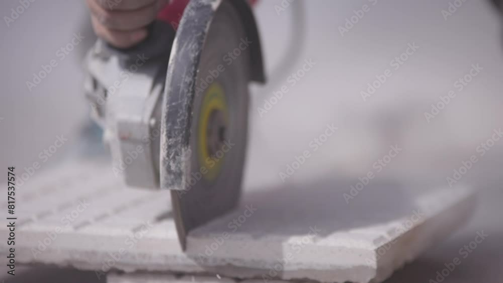 Trabajador corta una baldosa con una amoladora o radial. Herramienta de corte, Construcción y refacción. 