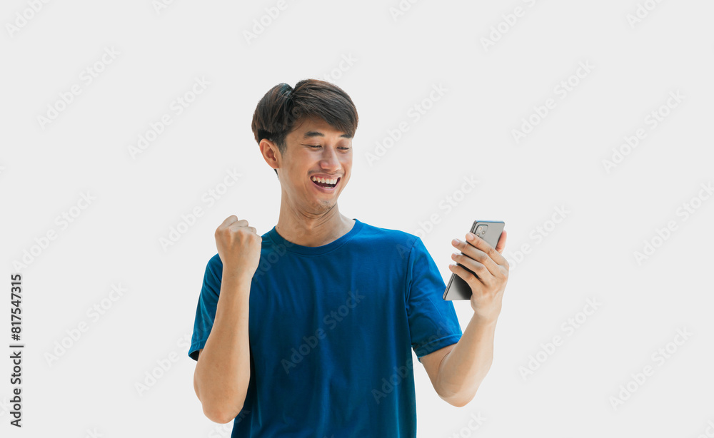 A handsome young Asian man smiling happily in a blue t-shirt is using his smartphone to shop online or chat with friends online. Man rejoicing from smartphone message winning lottery game