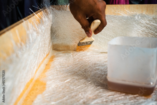 Brushing solution through fiberglass sheets on a wooden box. A diy project at home.