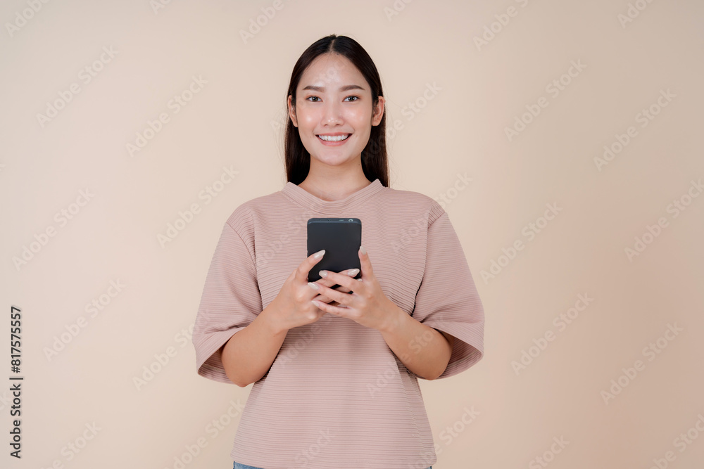 Smiling young woman using smartphone on beige background Smiling young woman using smartphone on beige background