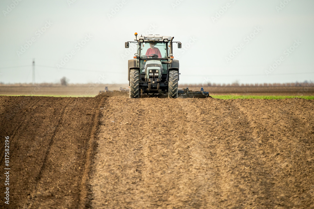 Fototapeta premium Powerful tractor with plow in action, turning the rich soil for new crops