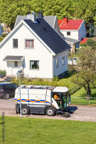 Street sweeper cleaning a city street in a residential area in the summer