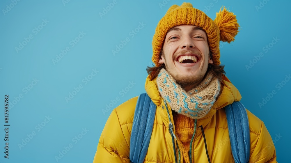  A man wears a yellow jacket, a blue and white scarf, and two yellow hats, one on his head and one around his neck