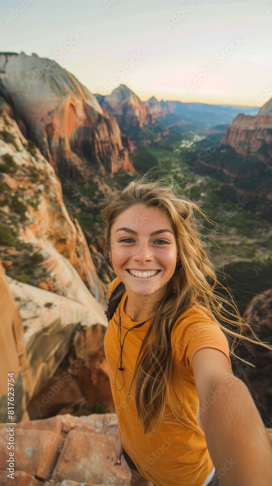A woman is smiling and taking a selfie in front of a mountain. The photo has a happy and adventurous mood