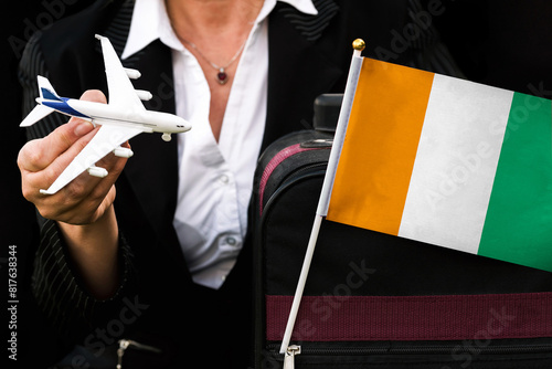 business woman holds toy plane travel bag and flag of Ivory Coast	