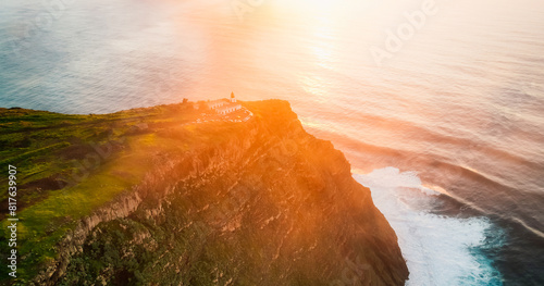 Aerial view of rough ocean with waves, volcanic beach, sunset over a huge cliff  in Lighthouse Ponta do Pargo, Madeira, Portugal photo
