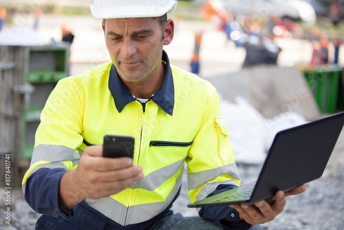 builder using a mobile phone and a laptop outdoors photo