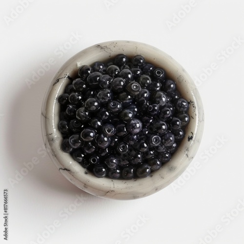 Black pearls neatly displayed in a bowl on a white surface photo