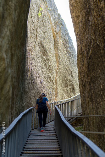 rear view of female who is hiking on mountain steel stairway through the rocks