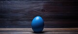 A blue egg nestled in a wooden background providing room for a copy space image