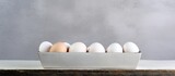 A container with white colored eggs on a concrete background providing ample copy space for additional images or text