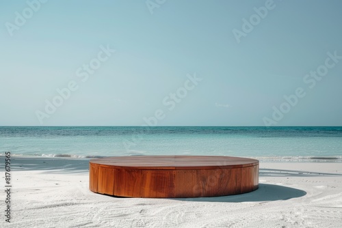 A round wooden table is placed on the sandy beach beside the ocean  with the sun shining brightly on its polished surface
