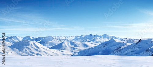 A panoramic view of a mountain slope under a clear blue sky and pristine white snow with plenty of copy space for an image