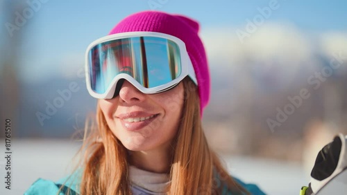 Close-up portrait of smiling woman snowboarder skyer in ski helmet and glasses in mountains, side view. Girl wearing in ski clothes in winter resort. Enjoy healthy active rest, snowboarding lifestyle. photo