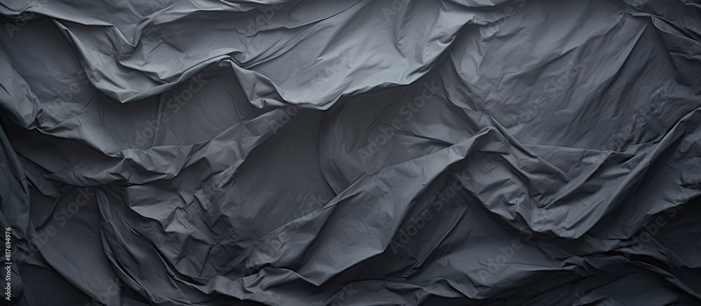 A crumpled piece of dark grey paper creates a textured background perfect for showcasing a copy space image A crumpled piece of dark grey paper creates a textured background perfect for showcasing a copy space image