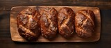 A top down view of three walnut bread loaves arranged neatly on an antique wooden cutting board with ample space for copy