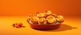 A bowl with freshly baked vegetable galettes placed on an orange background creating a visually appealing copy space image