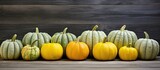 A copy space image of small yellow and green pumpkins arranged on a background of gray wooden planks