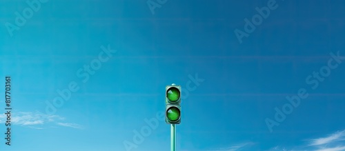 A green traffic light positioned on a pole above a road stands against a vibrant blue sky offering ample copy space