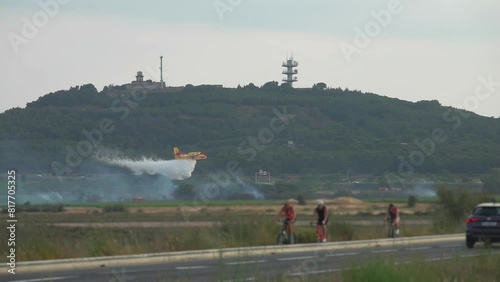 Yellow firefighting amphibious aircraft Canadair Bombardier 415 flies over the forest and dumps water to extinguish the fire photo