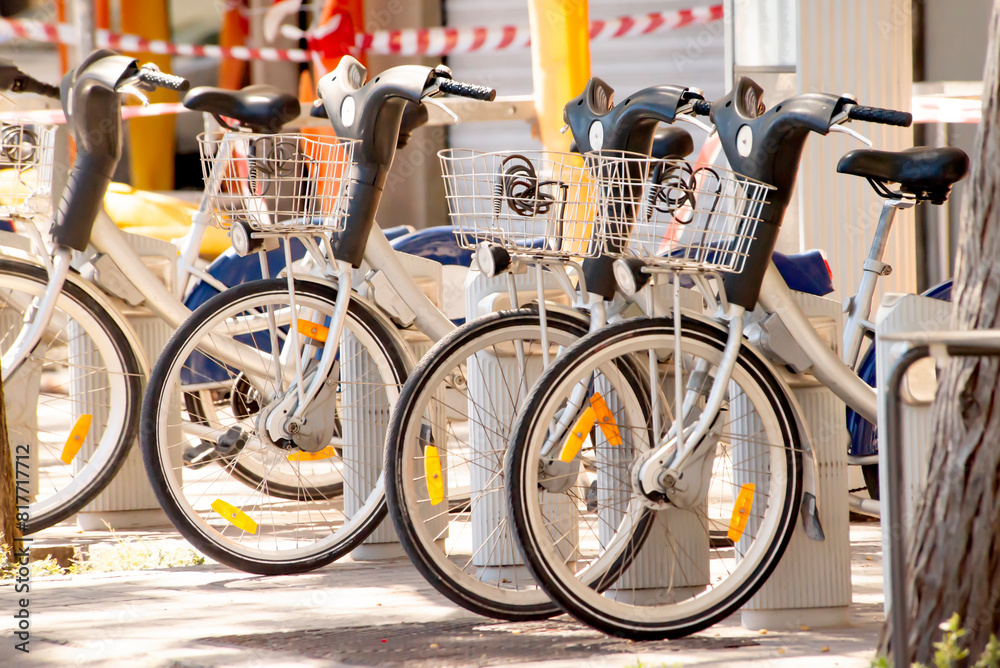 A group of rental electric bicycles parked at a docking station in an urban area with warning tape A group of rental electric bicycles parked at a docking station in an urban area with warning tape