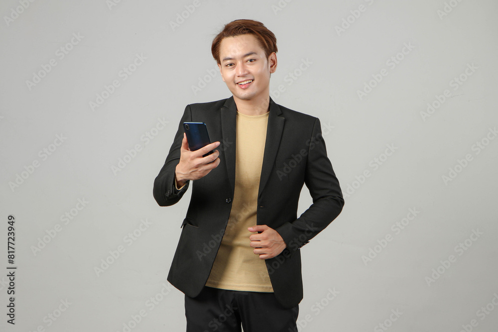 portrait of happy asian businessman wearing suit holding mobile phone on isolated background portrait of happy asian businessman wearing suit holding mobile phone on isolated background