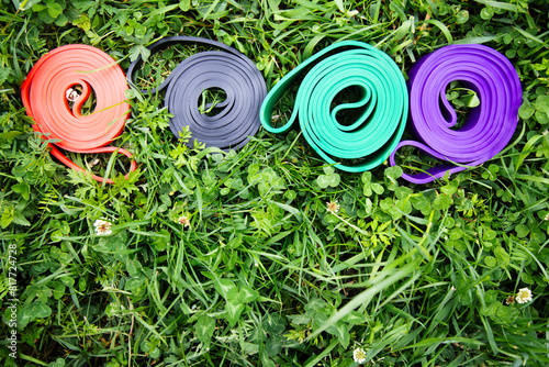 set of colorful elastic fitness bands  on green grass . Outdoor workouts concept . Top view , copy space